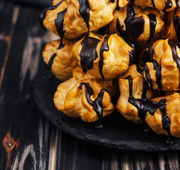 Profiteroles with chocolate cream on black plate