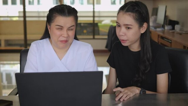 Asian women co-workers in workplace including person with blindness disability using laptop computer with screen reader program for visual impairment people. Disability inclusion at work.