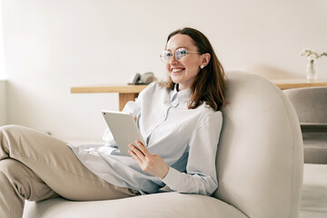 Using a tablet, a happy and cheerful young woman in a new stylish office, an application programmer.