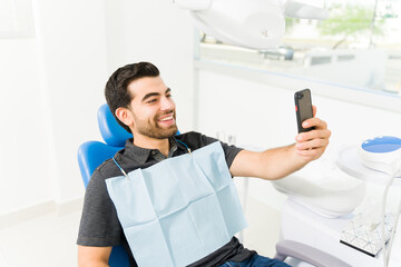 Cheerful man patient taking a selfie at the dentist