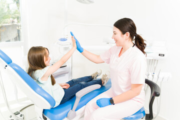 Happy female pediatric dentist celebrating with a kid patient