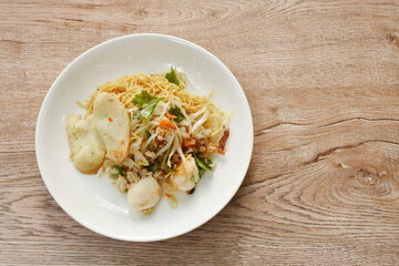 dry Chinese yellow egg noodles topping boiled chop pork and ball on plate