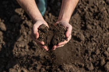 Male farmer in the field checks the soil. Selective focus.
