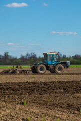The tractor plows the soil in the field. Selective focus.