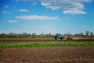 Obraz premium The tractor plows the soil in the field. Selective focus.