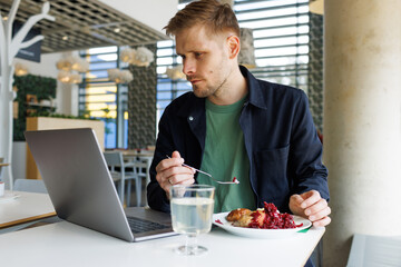 Fototapeta na wymiar Young male entrepreneur working from a cozy lounge, taking a break to enjoy a healthy eating lunch and watch a video. Reflects a modern workplace that emphasizes mindfulness and healthy living