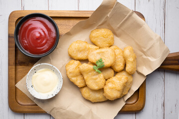 Nuggets on brown paper with ketchup on wooden table.