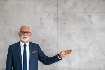 Naklejka premium Senior businessman posing on gray background, he is smiling at camera