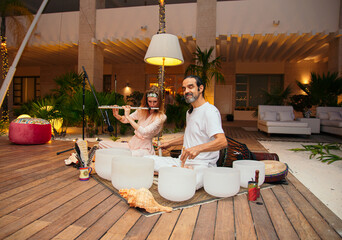 beautiful girl and mexican chaman playing tibetan bowls in a meditation ceremony
