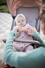 Woman on maternity leave taking out a child in a stroller, there is no face. Baby in stylish trendy clothes, a stroller on the street. Day, motherhood, mother, child care, happy childhood