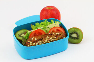 Whole grain oat roll with cheese, lettuce, cucumber, tomato in blue lunchbox and fresh fruit
