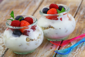 Nutritious breakfast: Greek yoghurt with granola, fresh strawberries, raspberries and blueberries in transparent glass
