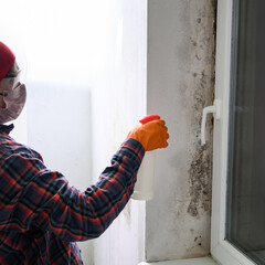 Mold and fungus on a plastic window, a woman removes mold on a window, a woman sprays chemicals on...