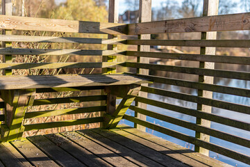 Wooden bench at the moorage. Recreational area by water. Sunny day, beautiful shadows. 