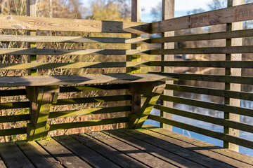 Wooden bench at the moorage. Recreational area by water. Sunny day, beautiful shadows. 