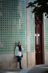 A woman talks on her cell phone while standing against the wall of a house in Porto downtown, Portugal.