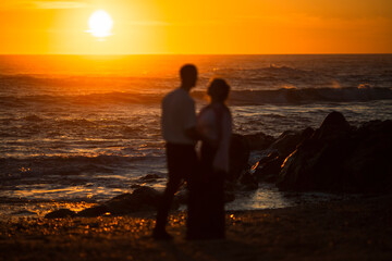 Blurry silhouettes of a couple in love on the ocean during a golden sunset.