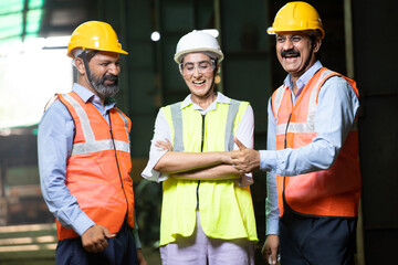 Team of happy confident indian engineers wearing safety hard hat and vest standing at industrial factory, male and female professional workers looking at camera, skill india.