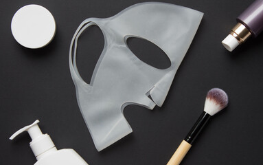 Cosmetics for face care with brush and silicone mask on black background, mockup. Health care concept. Top View.