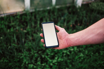 Gardener using mobile gardening app in greenhouse