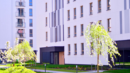 Ecology and green living in city, urban environment concept. Modern apartment building and green trees. Ecological housing architecture. A modern residential building in the vicinity of trees.