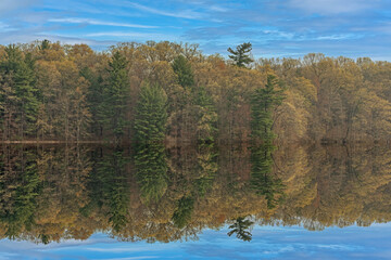 Spring landscape of the shoreline of Hall Lake with mirrored reflections in calm water, Yankee Springs State Park, Michigan, USA