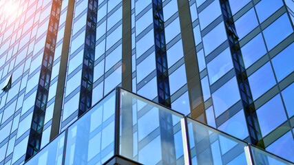 Windows of a modern glass building. Looking up at the commercial buildings in downtown. Modern office building against blue sky. 
