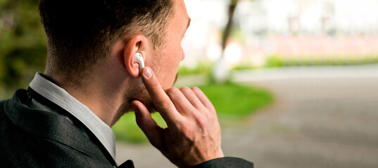 Close-up of an back Businessman showing his bluetooth headset with finger.