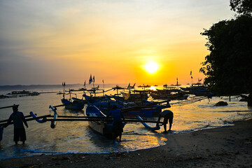 Fototapeta na wymiar Sunrise on Indonesian Pangandaran beach with white sand and fishing boats