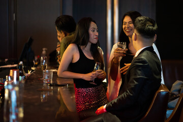 Diverse group of friends partying in nightclub and toasting drinks. Asian female drink intoxicating drink