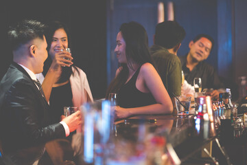 Diverse group of friends partying in nightclub and toasting drinks. Asian female drink intoxicating drink