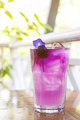 Butterfly pea with lemon juice on ice in take away glass with blur restaurant background. 