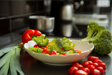 Cooking fresh vegetables salad in the kitchen at home. Healthy eating and lifestyle concept. Big wooden spoon mixing the dish