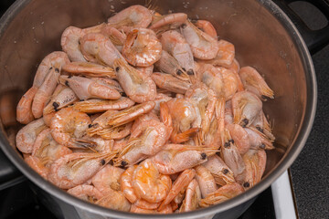 A lot of big shrimps, prawns are being cooked in the cooker 