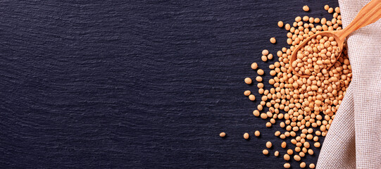 Soya beans with wooden spoon and burlap on the black surface of the slate stone, banner, top view, closeup with space for text - Powered by Adobe