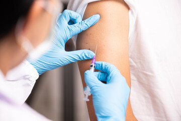 Doctor hand in blue gloves holding influenza vaccine for prevention human.Nurse holding syringe make injection in shoulder of patient in hospital.Covid-19 or coronavirus vaccine.