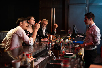 Peoples having fun watching football game on TV and drinking beverages at bar counter in nightclub