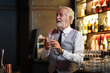 Professional expert barman making mix cocktail on counter bar at night club. Senior man