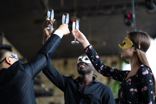 Masquerade party. Beautiful women and men wearing fantasy mask. Company employee enjoy drinking in mask party  together indoors celebration