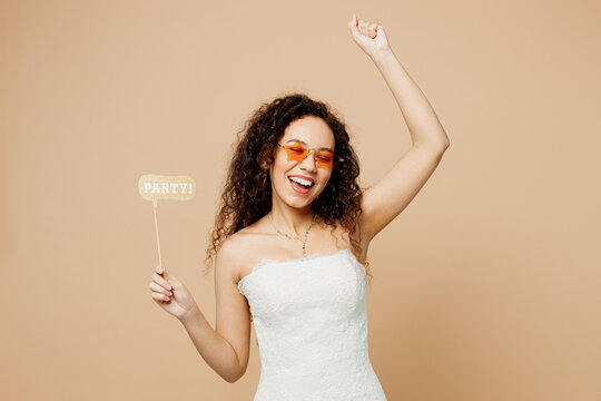 Happy young woman bride wear wedding dress glasses posing hold in hand photo props do winner gesture isolated on plain pastel light beige background studio portrait Ceremony celebration party concept