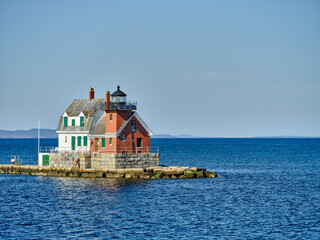The Rockland Breakwater Lighthouse as seen from the ferry heading back into Rockland harbor with the town of Rockland maine in the background