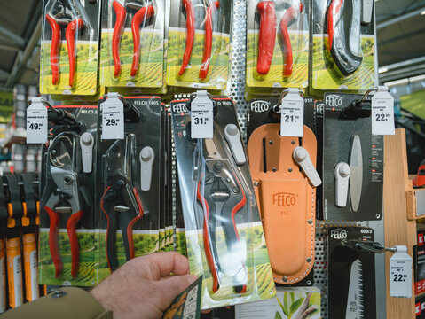 Frankfurt, Germany - Mar 4, 2023: A closeup view of a customer hand taking a red Felco brand pruner from the tool selection at an outdoor garden supermarket, made in Switzerland