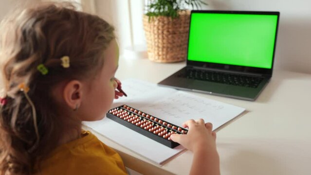 A girl from the back is engaged in mental arithmetic on the abacus online on a laptop, chroma key background. The concept of teaching children to count quickly, Russian mathematics.