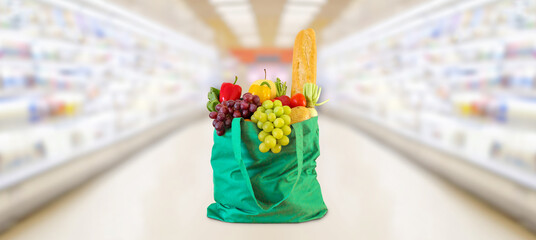 Shopping bag with fruits and vegetables in supermarket grocery store blurred background