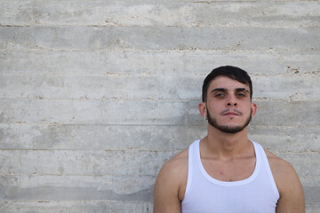 Fototapeta premium Young handsome man in white t-shirt making different expressions in front of grey wall. Man is happy and smiling. Concept different expressions.