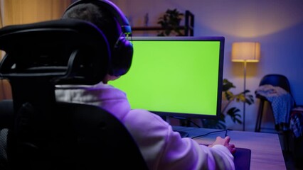 Young gamer plays game looking at monitor with chromakey