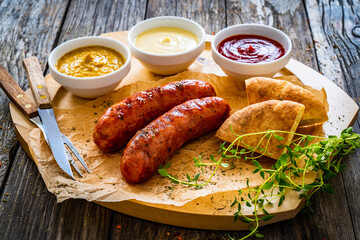 Fried sausages, onion and bread on wooden table
