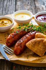 Fried sausages, onion and bread on wooden table
