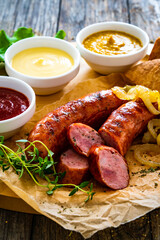 Fried sausages, onion and bread on wooden table
 - obrazy, fototapety, plakaty