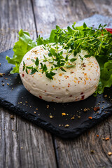 Cheese Robiola d'Alba with chili and thyme on black stone board on wooden table